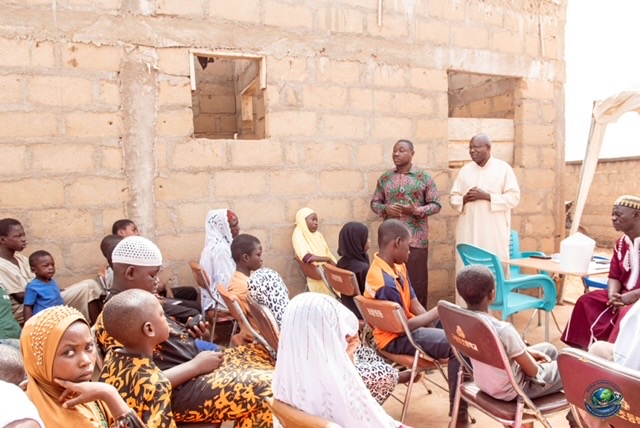 Children and guardians listening during the community meeting